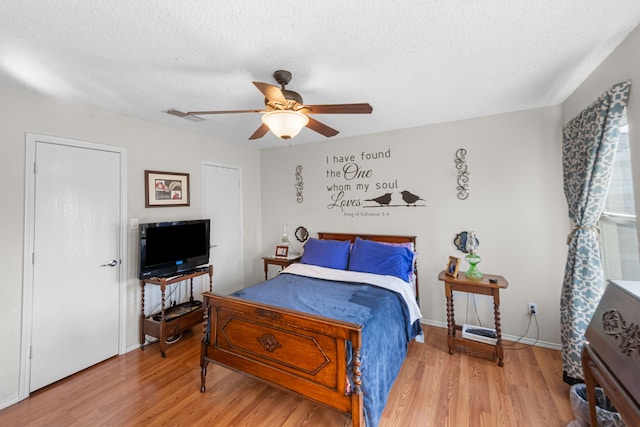 bedroom with ceiling fan, hardwood / wood-style flooring, and a textured ceiling