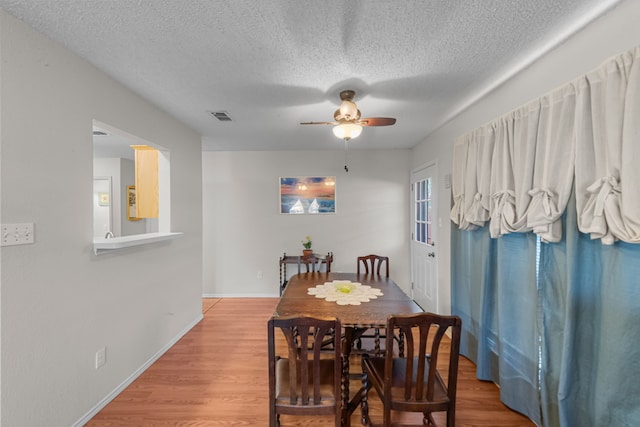 dining room with ceiling fan, wood-type flooring, and a textured ceiling