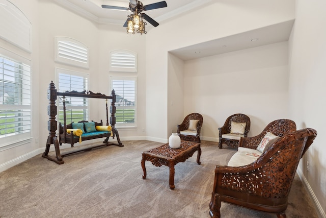 sitting room with crown molding, carpet, a towering ceiling, and ceiling fan