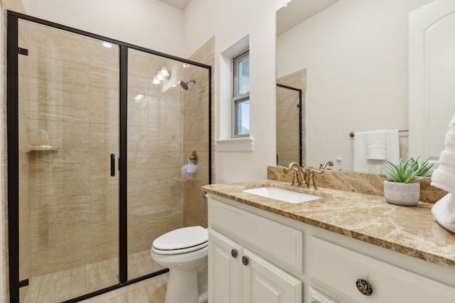 bathroom featuring vanity, a shower with shower door, and toilet