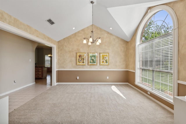 empty room with an inviting chandelier, high vaulted ceiling, and light colored carpet