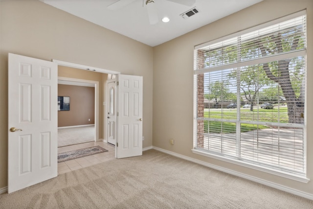 empty room featuring light carpet, ceiling fan, and a healthy amount of sunlight