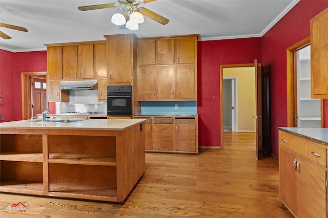 kitchen with black oven, ornamental molding, a center island, ceiling fan, and light hardwood / wood-style floors