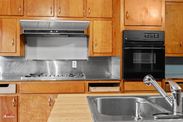 kitchen featuring sink, backsplash, black oven, and stainless steel gas cooktop