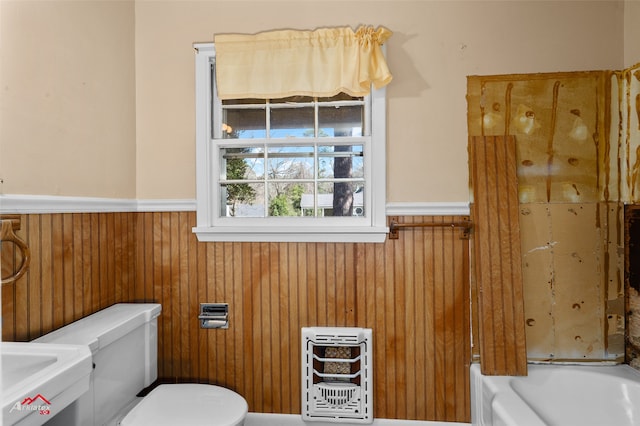 bathroom with toilet, wooden walls, a bath, and heating unit