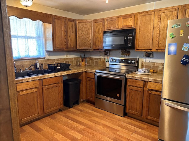 kitchen featuring stainless steel appliances, sink, and light wood-type flooring