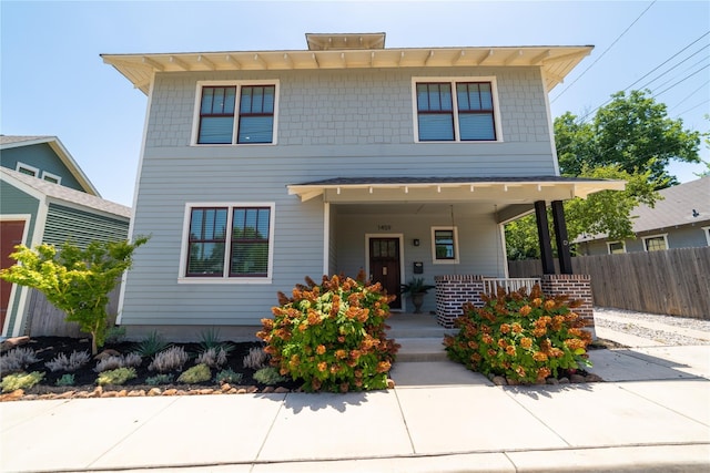 american foursquare style home with covered porch and fence