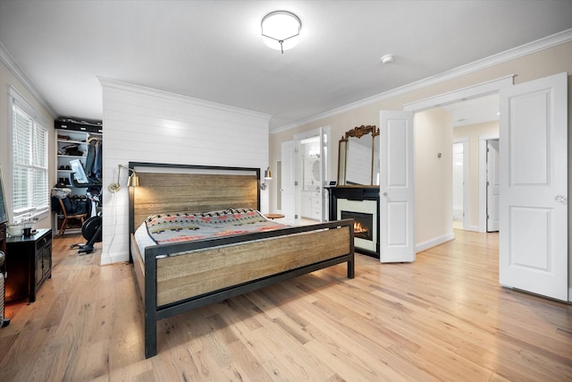 bedroom with crown molding, a spacious closet, and light hardwood / wood-style floors