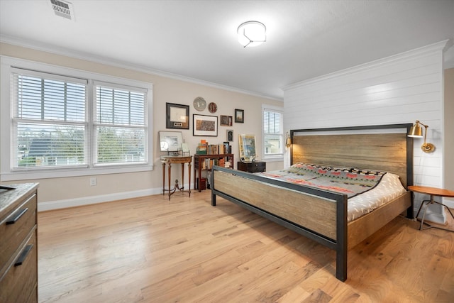 bedroom featuring multiple windows, ornamental molding, and light hardwood / wood-style flooring