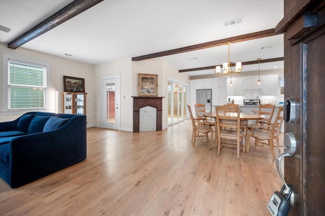 dining space featuring beamed ceiling, a notable chandelier, and light wood-type flooring