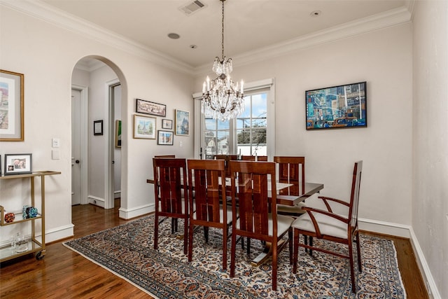 dining room with a notable chandelier, dark wood-type flooring, and ornamental molding