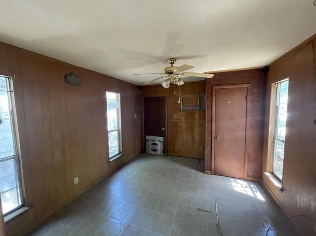 interior space with multiple windows, wooden walls, and ceiling fan