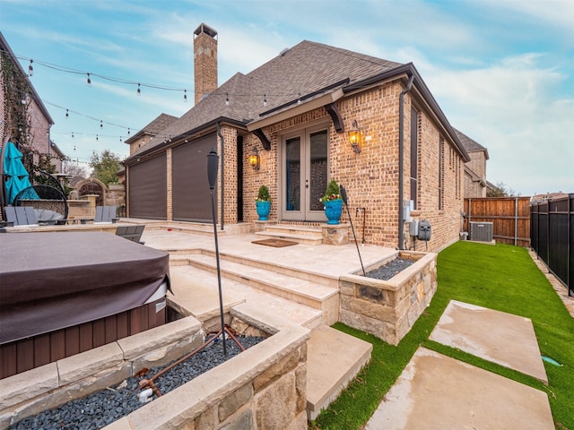 back of property with a yard, central AC, a hot tub, and a patio