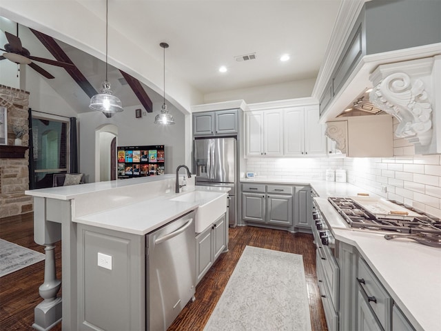 kitchen with pendant lighting, gray cabinets, appliances with stainless steel finishes, a kitchen island with sink, and dark hardwood / wood-style flooring