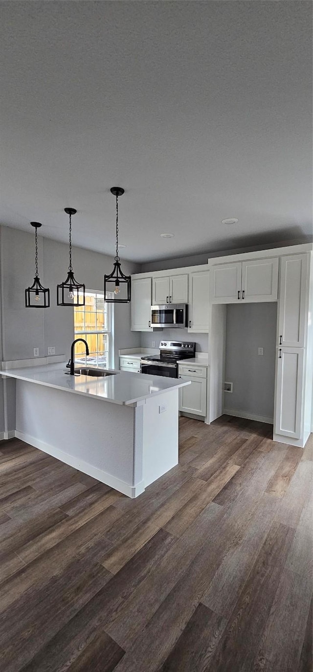 kitchen with dark wood-type flooring, sink, white cabinetry, hanging light fixtures, and stainless steel appliances