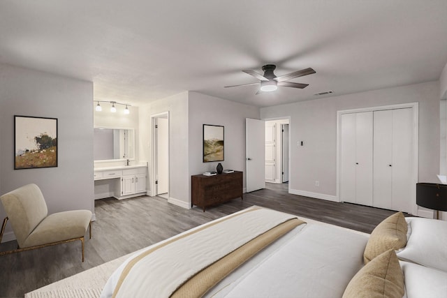 bedroom with ensuite bathroom, ceiling fan, visible vents, baseboards, and dark wood finished floors