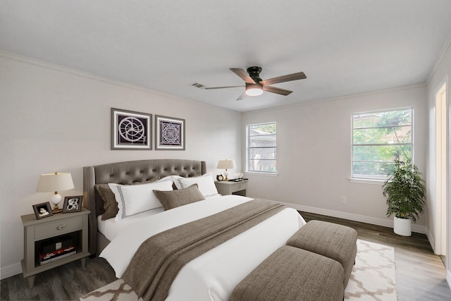 bedroom with crown molding, visible vents, ceiling fan, wood finished floors, and baseboards