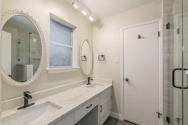 full bathroom with a sink, a shower stall, baseboards, and double vanity