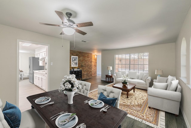 living room with light wood-type flooring, visible vents, arched walkways, and a ceiling fan