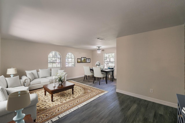 living room with a ceiling fan, visible vents, dark wood finished floors, and baseboards