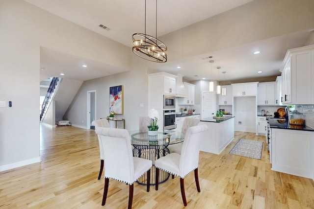 dining area with light wood finished floors, visible vents, recessed lighting, and a chandelier