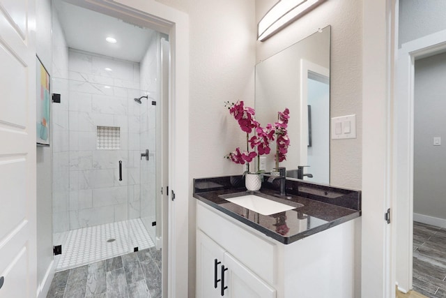 bathroom with a shower stall, wood finished floors, vanity, baseboards, and recessed lighting