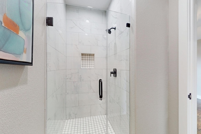 full bathroom with a shower stall and a textured wall