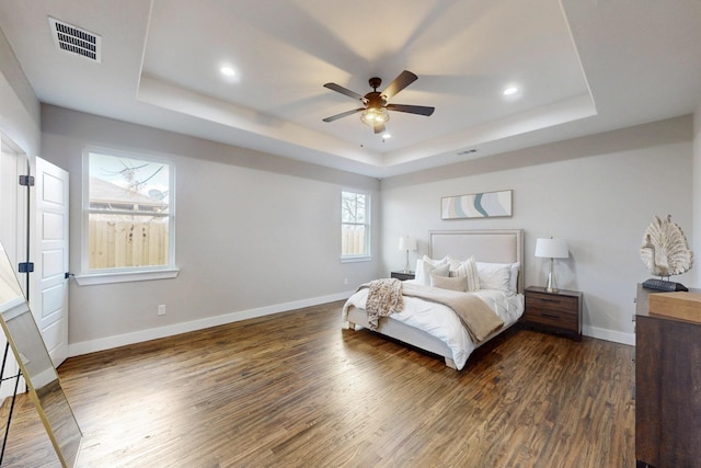 bedroom with recessed lighting, a raised ceiling, visible vents, dark wood-type flooring, and baseboards