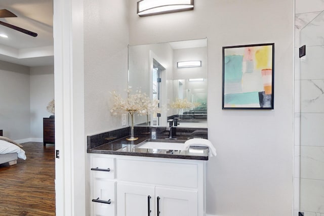ensuite bathroom with wood finished floors, vanity, ensuite bath, baseboards, and ceiling fan