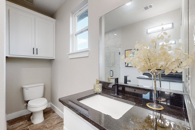 bathroom with toilet, wood finish floors, vanity, visible vents, and a shower stall