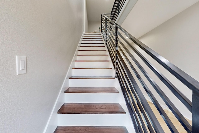 stairway with a textured wall and wood finished floors