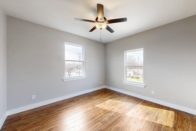 empty room featuring ceiling fan, plenty of natural light, baseboards, and wood finished floors