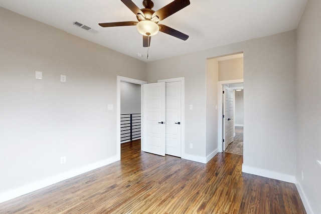 unfurnished bedroom featuring ceiling fan, wood finished floors, visible vents, and baseboards