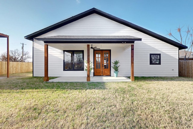 view of front of property with french doors, a front lawn, ceiling fan, and fence