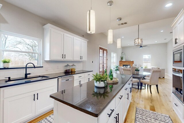 kitchen with a ceiling fan, a sink, light wood-type flooring, stainless steel appliances, and visible vents
