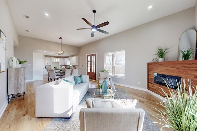 living room with ceiling fan, recessed lighting, baseboards, light wood finished floors, and a glass covered fireplace