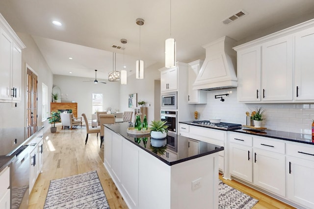 kitchen with premium range hood, light wood-style flooring, visible vents, and appliances with stainless steel finishes