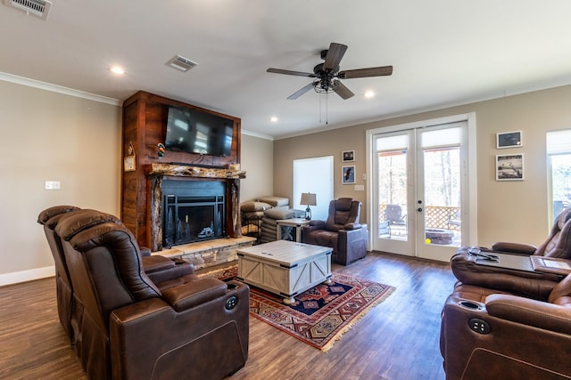 living room featuring ornamental molding, dark wood-style flooring, visible vents, and a fireplace with raised hearth