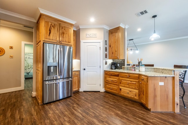 kitchen featuring a peninsula, visible vents, a kitchen breakfast bar, stainless steel fridge, and decorative light fixtures