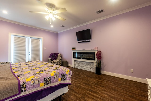 bedroom featuring baseboards, visible vents, ornamental molding, dark wood-style flooring, and a stone fireplace