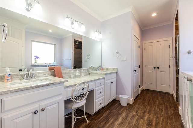 bathroom with crown molding, double vanity, a sink, and wood finished floors