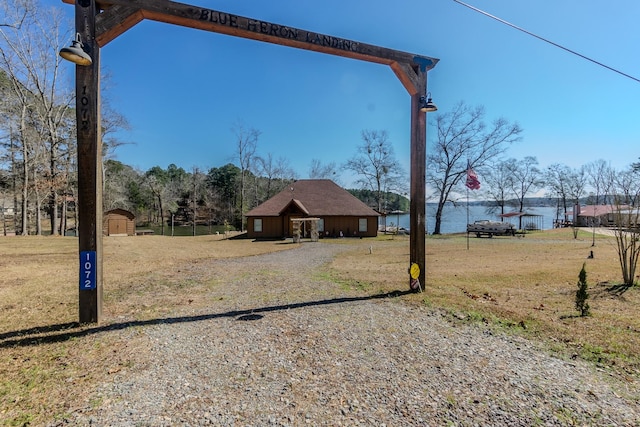 view of yard featuring a water view, an outdoor structure, driveway, and a storage unit