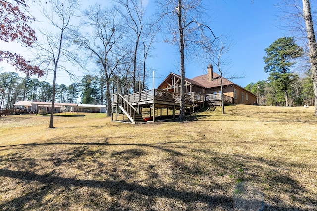 rear view of property with a chimney, stairway, a lawn, and a wooden deck