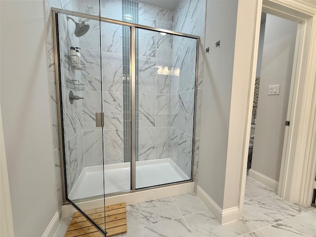 full bath featuring baseboards, marble finish floor, a marble finish shower, and toilet