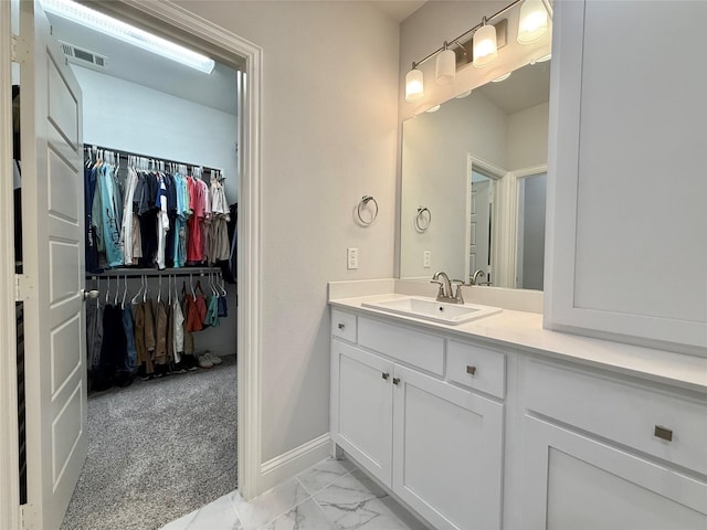 bathroom featuring vanity, marble finish floor, a spacious closet, visible vents, and baseboards