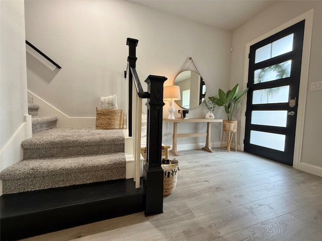 entrance foyer featuring stairs, baseboards, and wood finished floors