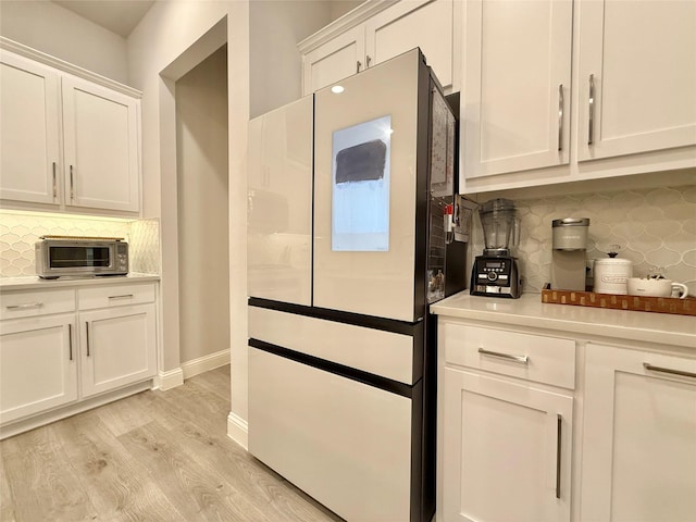 kitchen featuring white fridge, light hardwood / wood-style floors, decorative backsplash, and white cabinets