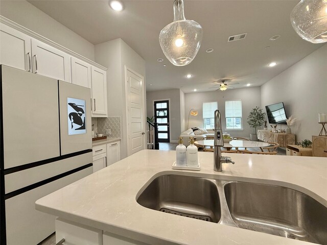 kitchen with visible vents, white cabinets, a sink, and freestanding refrigerator