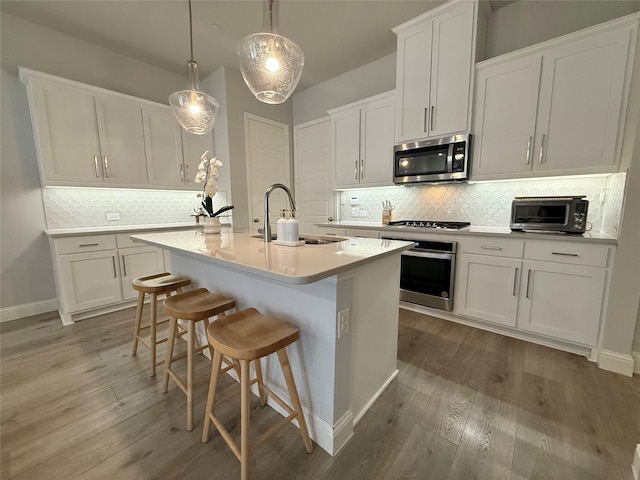 kitchen featuring a kitchen island with sink, appliances with stainless steel finishes, light countertops, and a sink