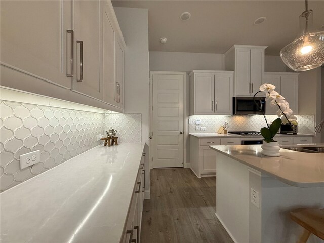 kitchen featuring decorative light fixtures, light countertops, white cabinetry, and stainless steel microwave